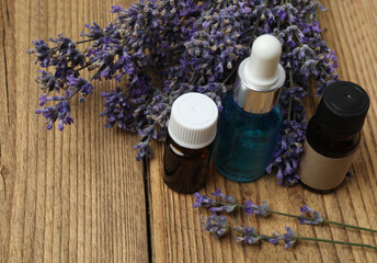 Bottles with lavender oil, lavender on wooden background