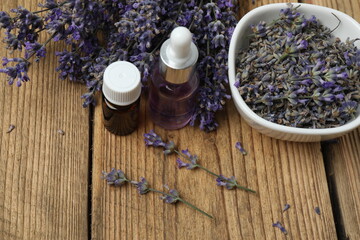 Bottles with lavender oil, lavender on wooden background