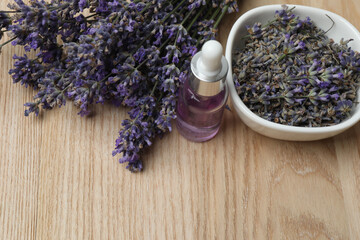 Bottles with lavender oil, lavender on wooden background