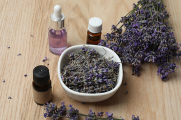 Bottles with lavender oil, lavender on wooden background