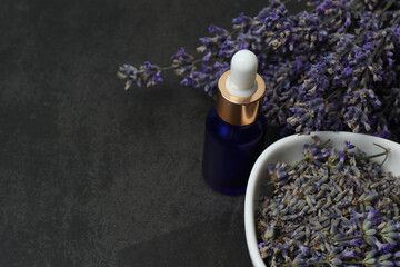 Bottles with lavender oil, lavender on black marble background