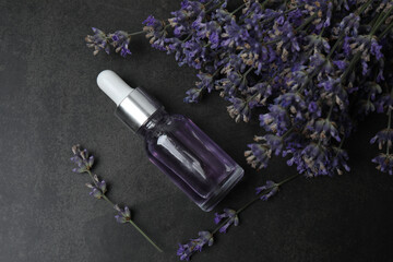 Bottles with lavender oil, lavender on black marble background