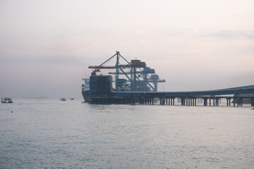 Cilegon, Indonesia-September 14, 2023: Container ship docked at a port with cranes and a pier,...