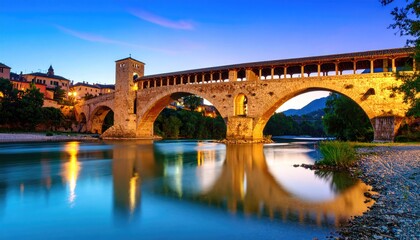Fototapeta premium Ancient bridge over calm river at dusk