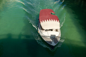 pleasure boat with the Qatari flag sails along the canal in the little Venice district....