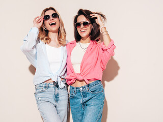 Two young beautiful smiling brunette and blond female in trendy summer clothes. Carefree women...