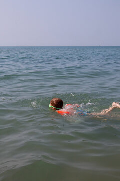 A small boy wearing floaties and mask swimming in the sea