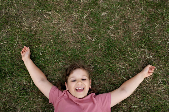 Happy child girl laughing and lying on the grass.