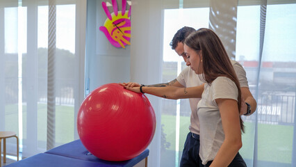 Physiotherapist helps a young woman perform shoulder stretching exercises for rehabilitation