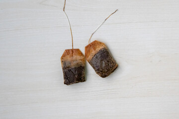 After brewing milk tea, two used black tea bags rest on a wooden background. Great for compost,...