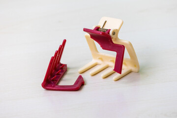 Broken old hair claw clip on wooden surface with damaged parts. Damaged woman's hair accessory,...