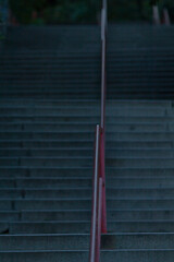A person is slowly walking down a set of stairs that features a bright red railing, creating a...