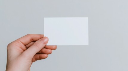 A hand holding a blank white card
