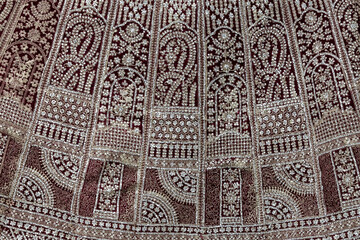 Intricate beadwork on an embroidered lehenga, captured in a detailed close-up texture background....