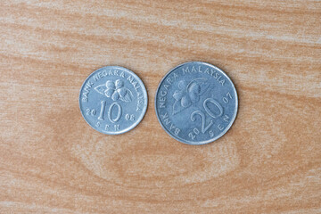 Old Malaysian 10 sen coin 2008 and 20 sen coin 2007 on wooden background. Stainless steel Malaysian Ringgit currency, Bank Negara Malaysia, top view.