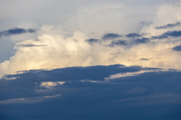 Fototapeta premium Bluish afternoon sky with dramatic dark and white clouds floating. Capturing the essence of bad weather and stormy atmospheric conditions.
