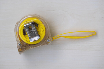 Classic measuring tape resting on a wooden surface. An indispensable tool used to precisely...
