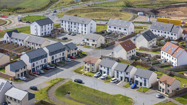 Aerial view of neat rows of modern houses with grey roofs, interspersed with occasional red brick accents, Newton Village, Dalkeith, Scotland, United Kingdom.