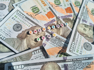 Concept image of emergency fund with dollar bills and colorful alphabet beads
