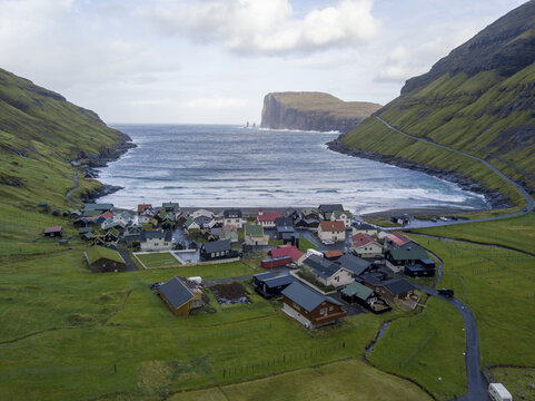 Aerial view of a quaint village nestled between verdant hills and the dramatic coastline, where houses form a colorful mosaic against the moody sea, Tj&Atilde;&cedil;rnuv&Atilde;&shy;k, Streymoy, Faroe Islands.