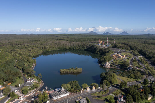 Aerial view of the serene lake mirroring the sky, surrounded by lush forests and temples, creating a vibrant contrast of nature and architecture, Baie du Cap, Savanne District, Mauritius.