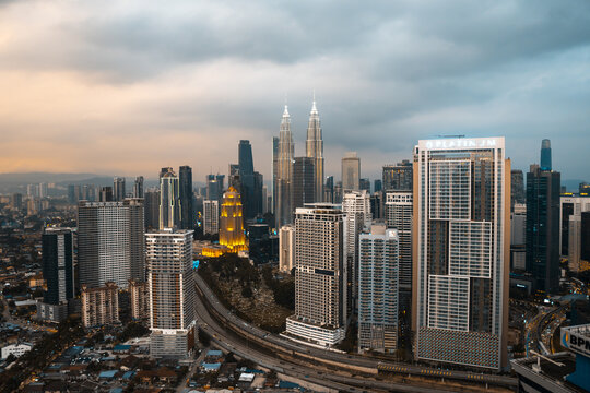 Kuala Lumpur, Malaysia - 27 June 2025: Aerial view of a modern cityscape dominated by the iconic Petronas Twin Towers under a dramatic, textured sky.