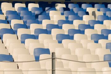 Rows upon rows of blue and white seats can be found in a large stadium, showcasing a vibrant sports...
