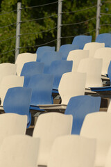 A long row of blue and white chairs is found within a stadium setting, offering seating for...