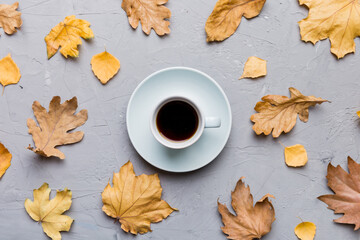 Flat lay composition with colorful Autumn cup of coffee and leaves on a color background. top view