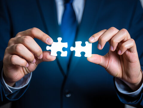 Man holding puzzle pieces represents problem solving, teamwork and finding solutions in a business context.