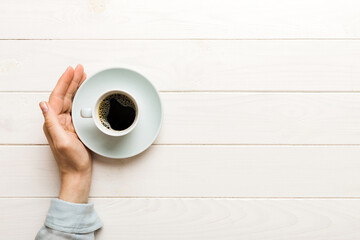 Minimalistic style woman hand holding a cup of coffee on Colored background. Flat lay, top view...