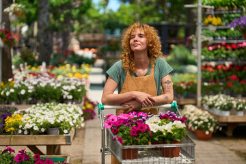 Florist pushing cart with colorful flowers in garden center