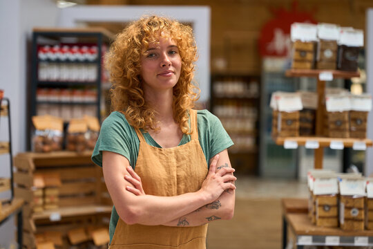 Confident saleswoman with folded arms in organic food store