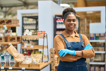 Confident saleswoman smiling with crossed arms in grocery store