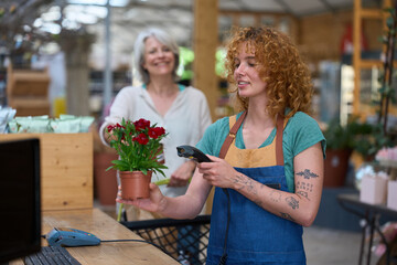 Florist scanning red carnations in flower shop during purchase