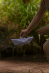 A woman is gently holding a delicate paper boat in her hand, showcasing her creativity on this...