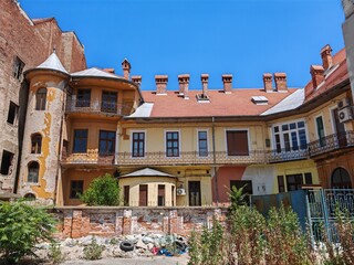 Zaniedbany wewnętrzny dziedziniec starej kamienicy z wieżyczką w Oradei, Rumunia – architektura i ślady upływu czasu