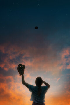 Girl throwing softball in air with sunset background