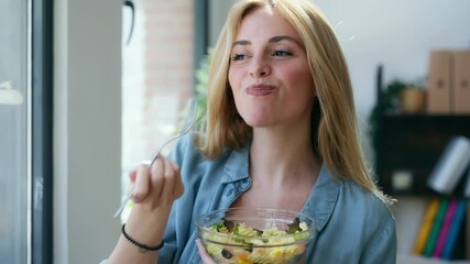 Video of smiling woman eating healthy pasta salad while sitting on the living room at home