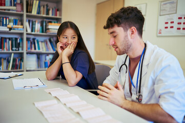Doctors collaborating, discussing medical charts in hospital room