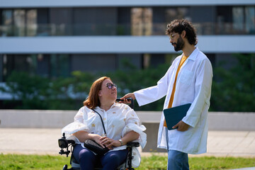 Doctor comforting disabled woman in wheelchair in the park - wheelchair and disability concept