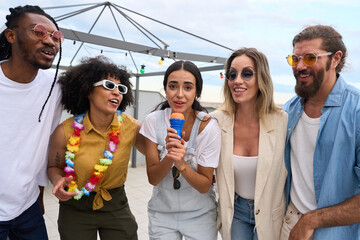 Friends singing karaoke outdoors at rooftop party
