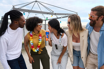 Friends singing karaoke at rooftop party with microphone