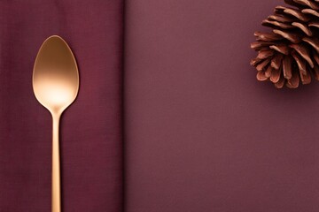 Elegant table setting with a copper spoon and natural pinecone decoration