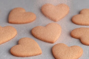Sweet heart-shaped cookies covered with sugar dust at a cozy kitchen table
