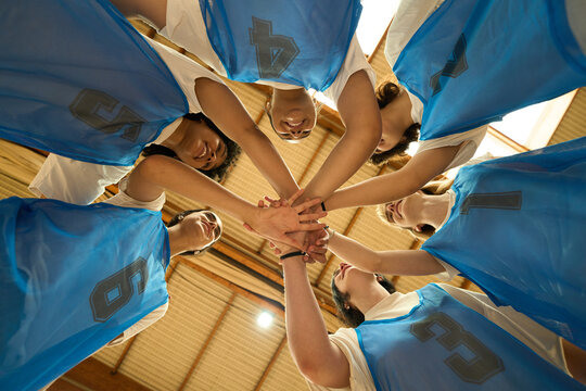 Female basketball team joining hands before game