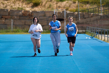 Determined female athletes running on blue track