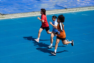 Determined female athletes running on blue track