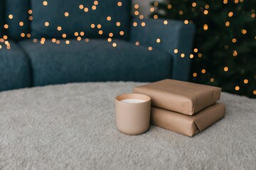 Cozy holiday corner with wrapped gifts and a candle glowing softly