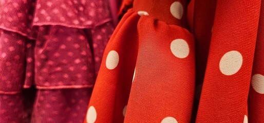 Red fabric with bold white polka dots next to textured magenta cloth featuring layered ruffles and...
